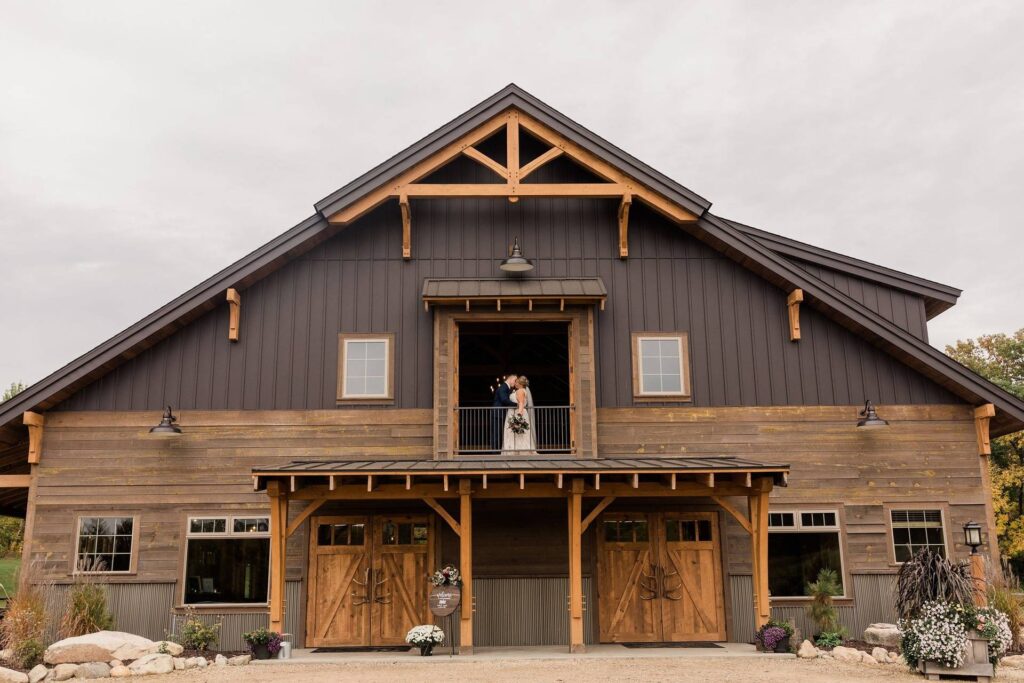 Rustic barn with couple on balcony.
