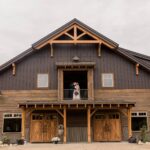 Rustic barn with couple on balcony.