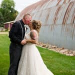 Couple kissing near rustic barn.